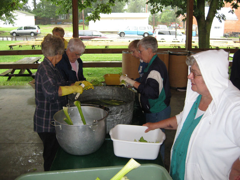 Volunteers, including Sara Schone, June Houston, and Brenda Beets, work at cleaning and trimming stalks of celery.