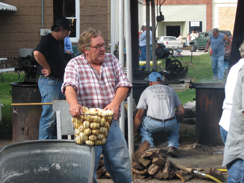 Tom Anderson heaves a bucket of peeled potatoes out of the tank to carry them to a table of volunteers who are chopping them into quarters.