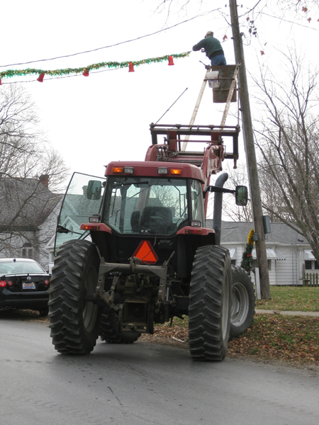 Placing garland over the streets, with the help of the lift on the tractor.